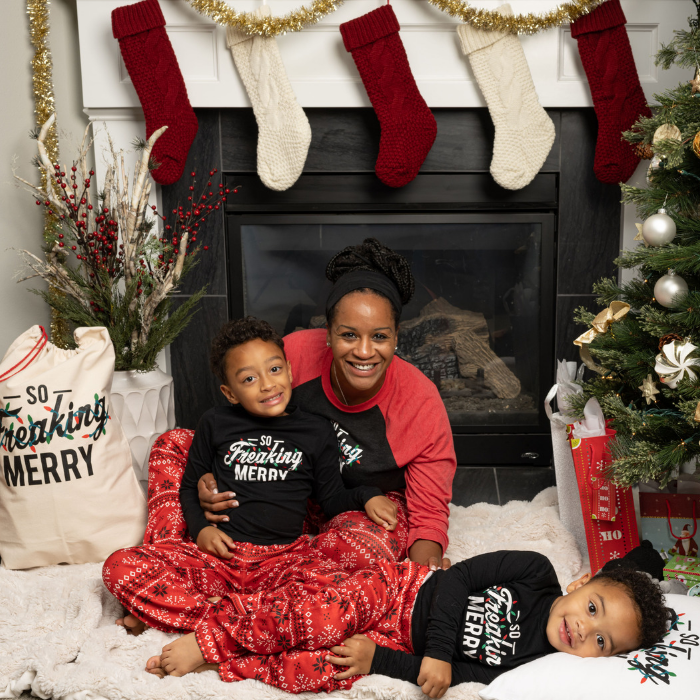 Red Fair Isle family wearing So Freaking Merry shirts in front of a fireplace