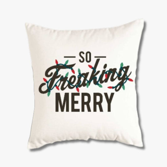 White throw pillow cover saying So Freaking Merry in black with multi colored lights strung around it